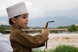 Omani boy taking pictures of a flooding wadi in Nizwa.