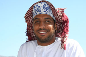Un omanais souriant, vêtu des traditionnelles dishdasha et kuma. 