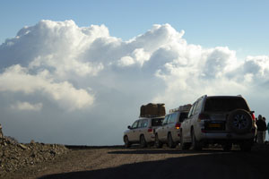 Voitures sur le Jebel Shams, avec des nuages blancs en arrière-plan.